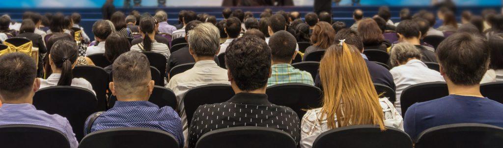 Photo from the back of people sitting in an auditorium.