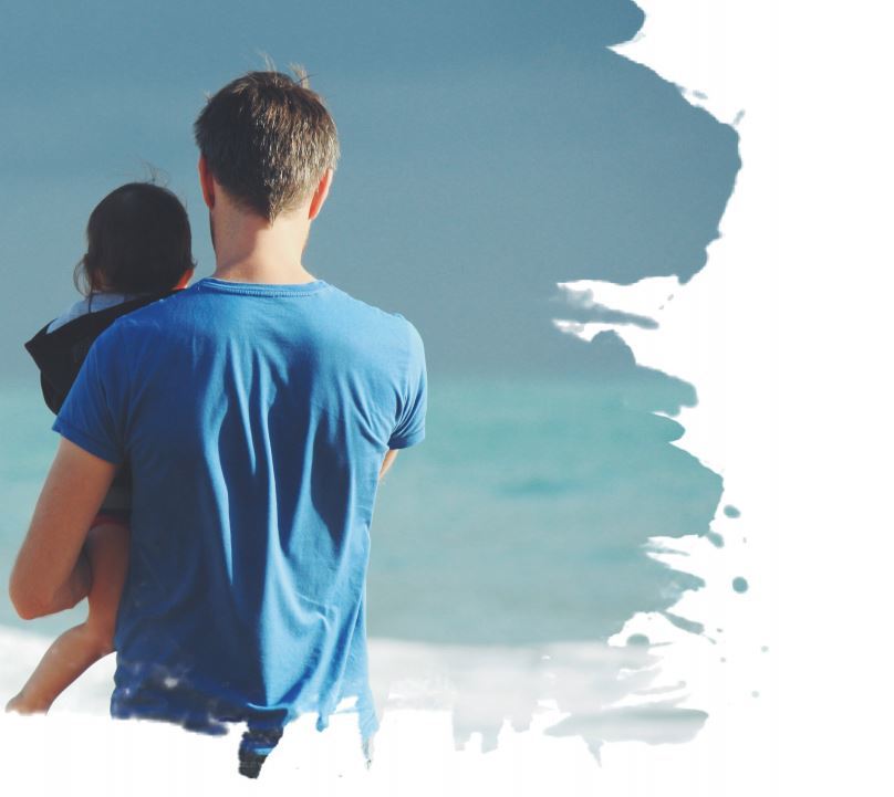 Father holding daughter at seaside