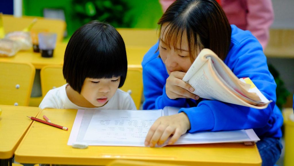 Child and teacher over a book