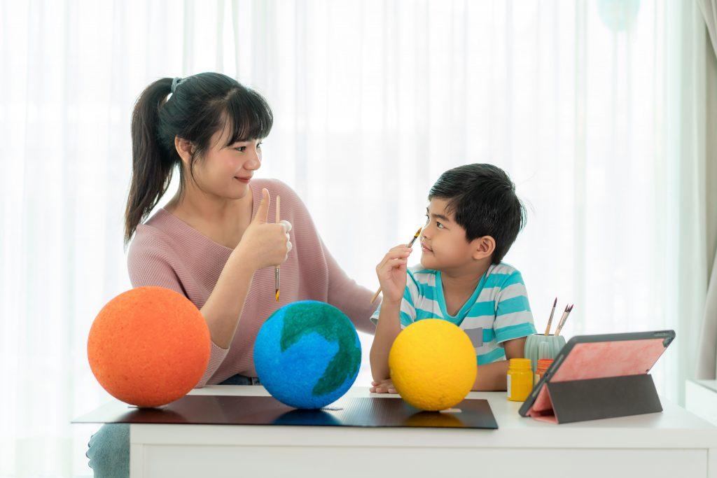 Woman and child look at one another holding paint brushes