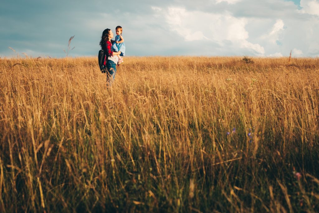 Mother holding toddler aged daughter in a wheat field.